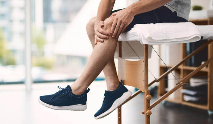 Patient sitting on bench holding knee