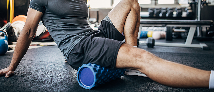 Adult using foam roller on thigh inside a gym