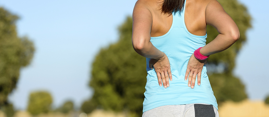 image of adult woman holding holding her back in pain