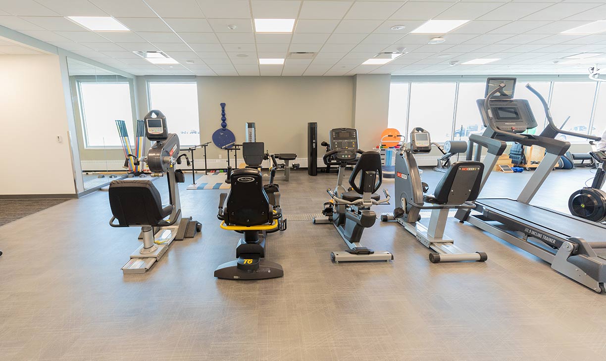 Physical therapy gym with stationary bikes, a treadmill, and other equipment