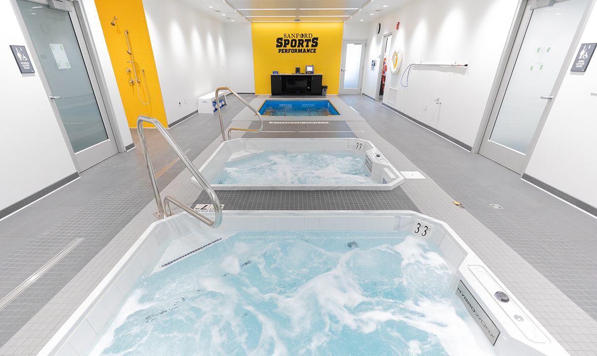 Therapy pools in a white room with a yellow wall in a distance where the employee desk is located
