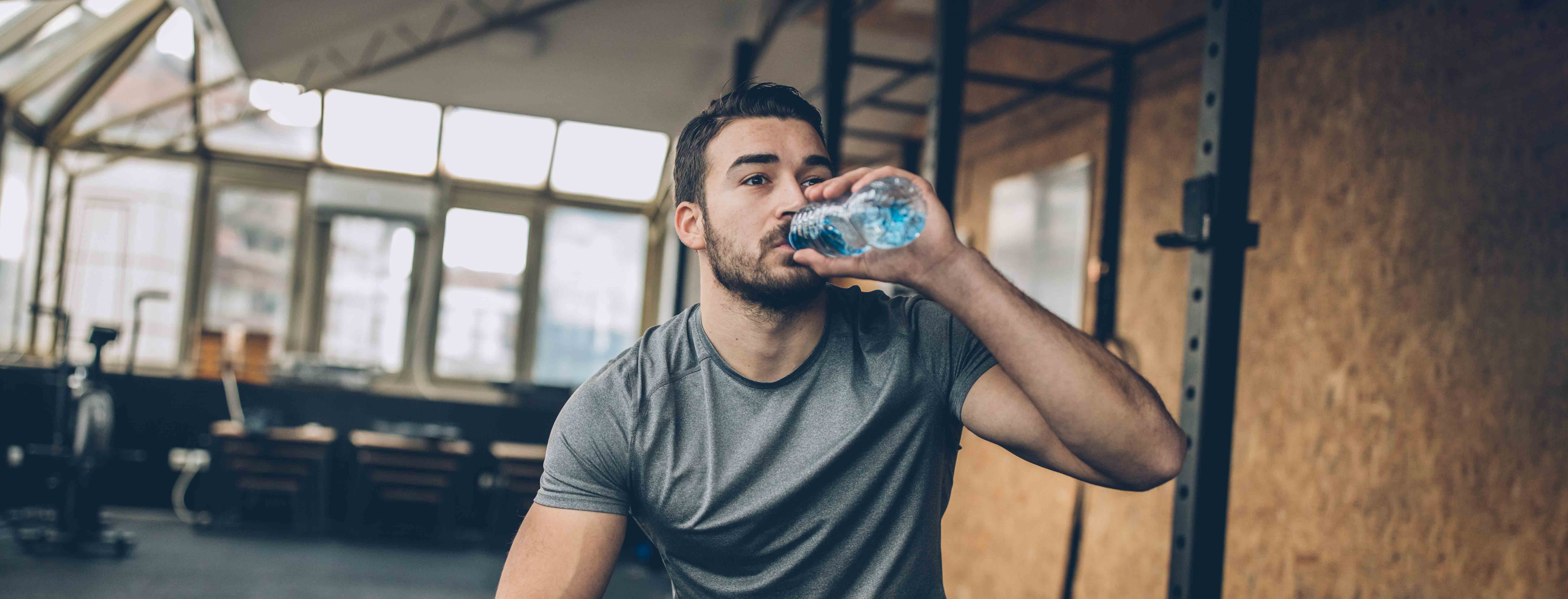 person drinking water in weight room