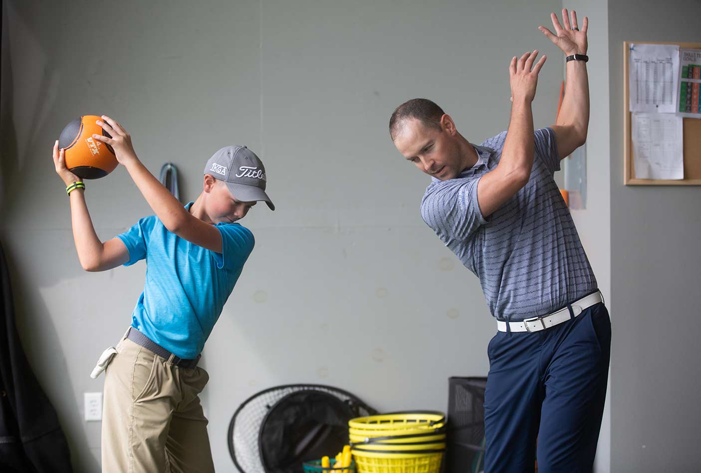kid and adult practicing golf together
